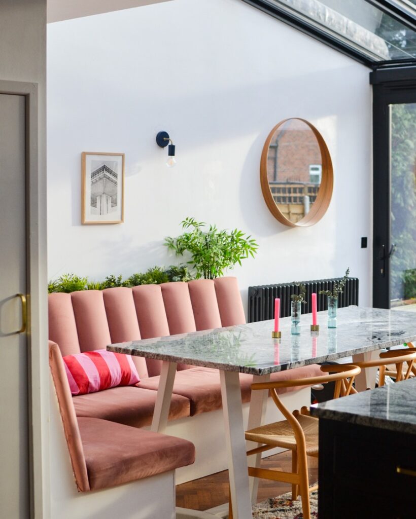 Open plan kitchen diner. Pink velvet bench seating area with marble dining table. Carl Hansen Wishbone chairs.